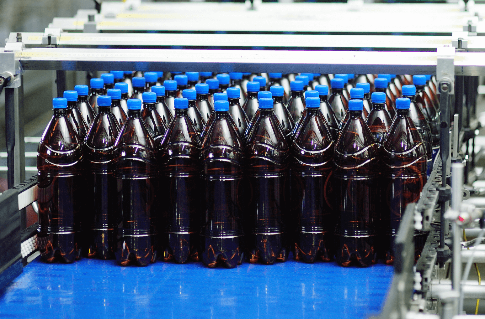 Bottles with blue caps on a conveyor belt pep+ goals
