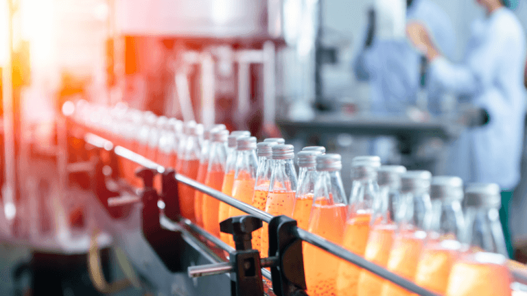 Orange bottles on a production line at a bottling plant with a light overlay on the left side.