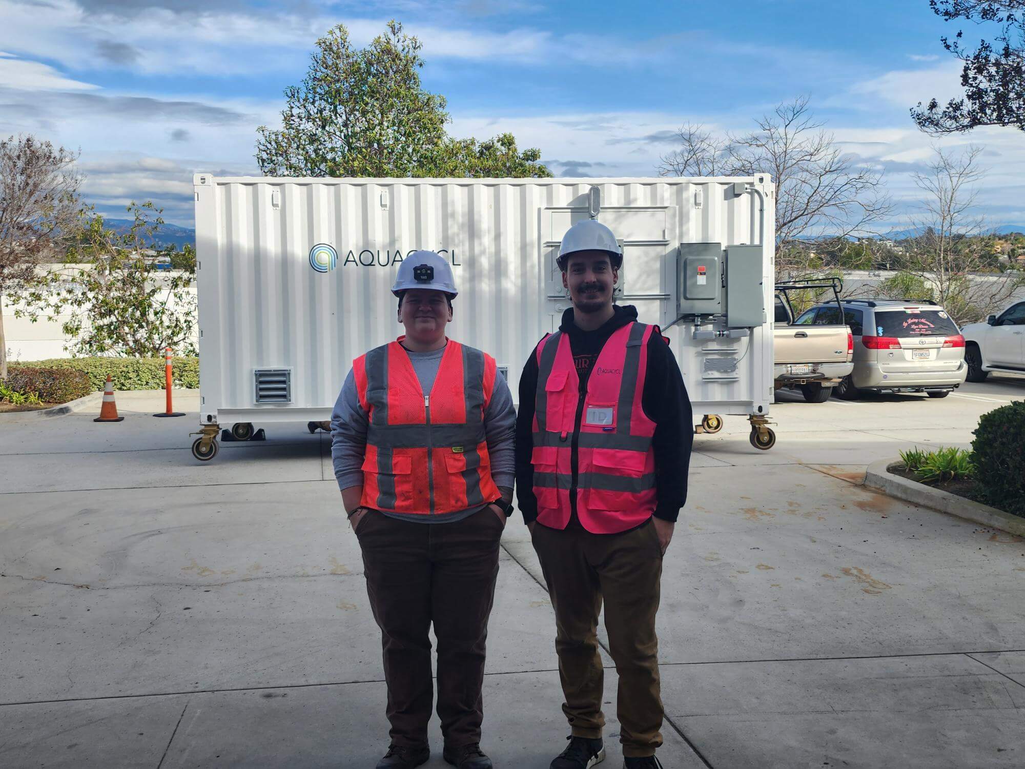 Two service technicians standing in front of an Aquacycl container