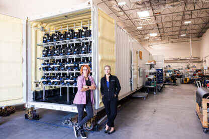 Orianna Bretshcger and Sofia Babanova standing in front of the BETT system in the Aquacycl warehouse